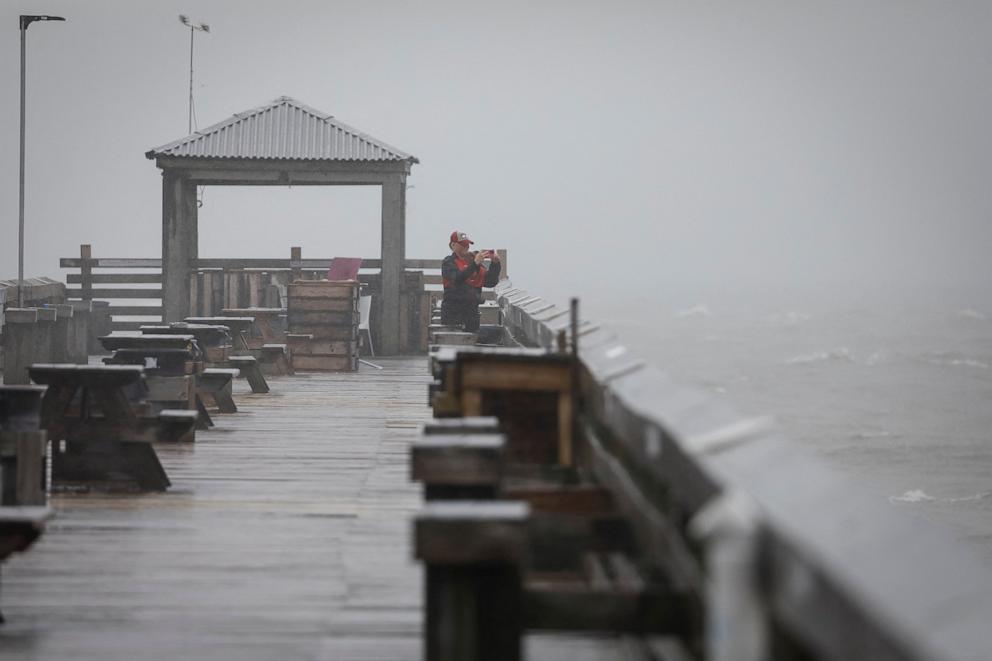 PHOTO: A woman uses her phone to capture images from the pier as Tropical Storm Debby drifts in the East Coast, in Myrtle Beach, South Carolina, U.S., August 7, 2024.