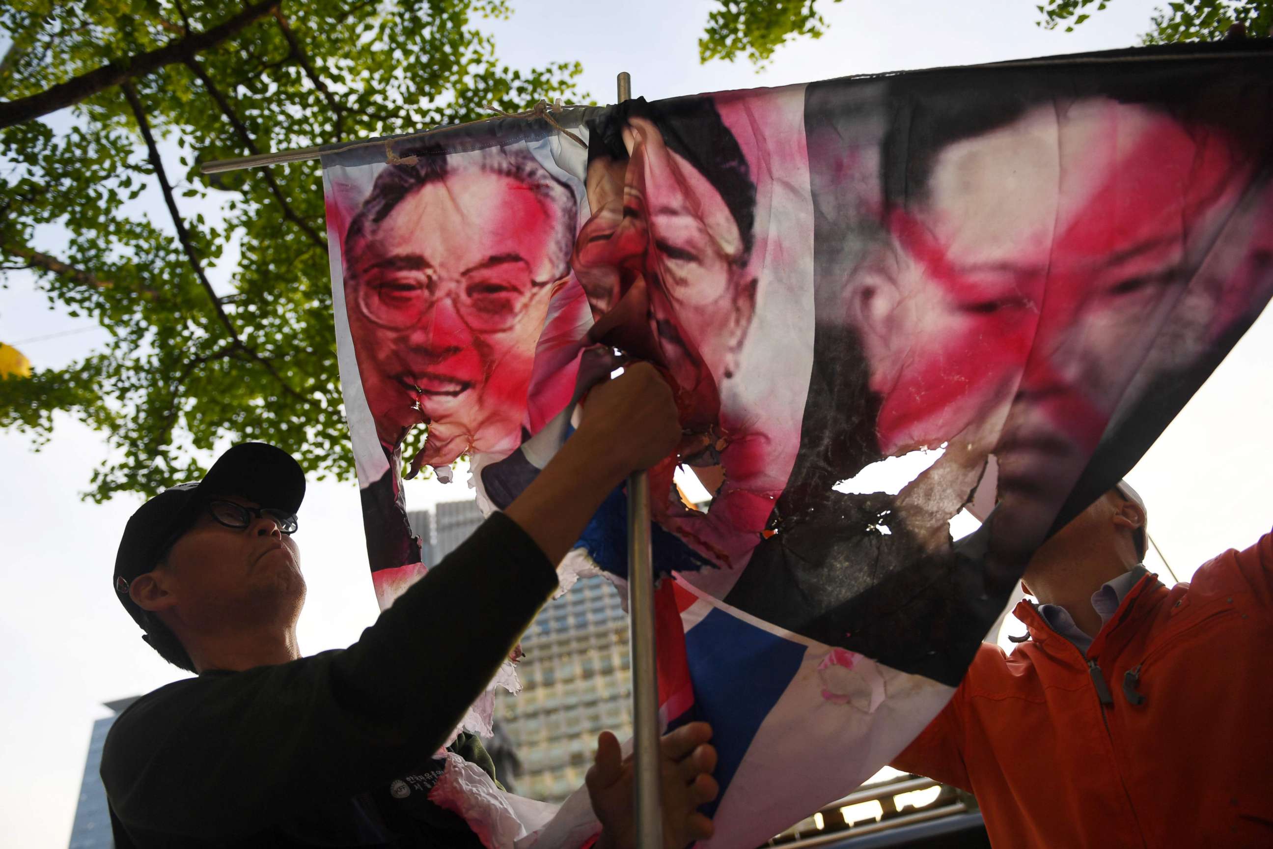PHOTO: An holds partially burnt images of late North Korean leaders Kim Il Sung, Kim Jong Il, and current leader Kim Jong Un, during a protest opposing the inter-Korean summit in Seoul on April 26, 2018.
