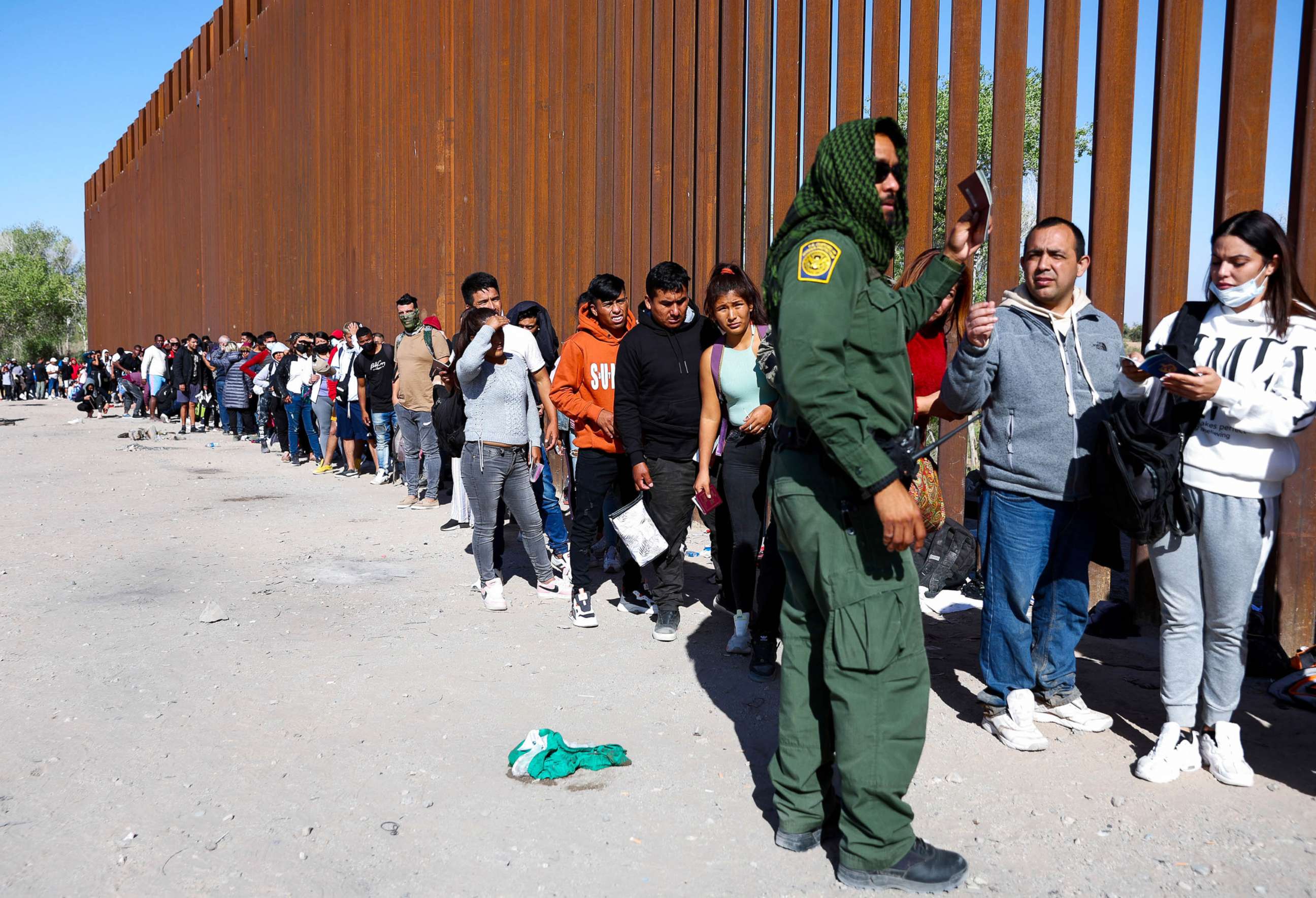 PHOTO: A U.S. Border Patrol agent checks for identification of immigrants as they wait in line to be processed after crossing from Mexico in Yuma, Ariz., May 21, 2022.