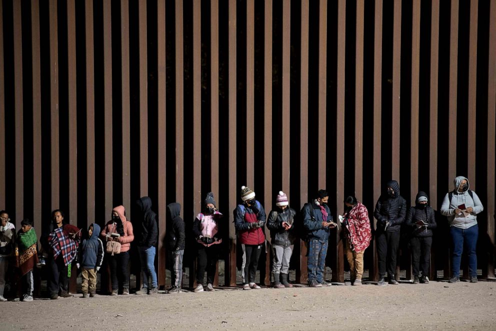 PHOTO: Asylum-seekers line up to be processed by US Customs and Border Patrol agents at a gap in the US-Mexico border fence near Somerton, Arizona, Dec. 26, 2022.
