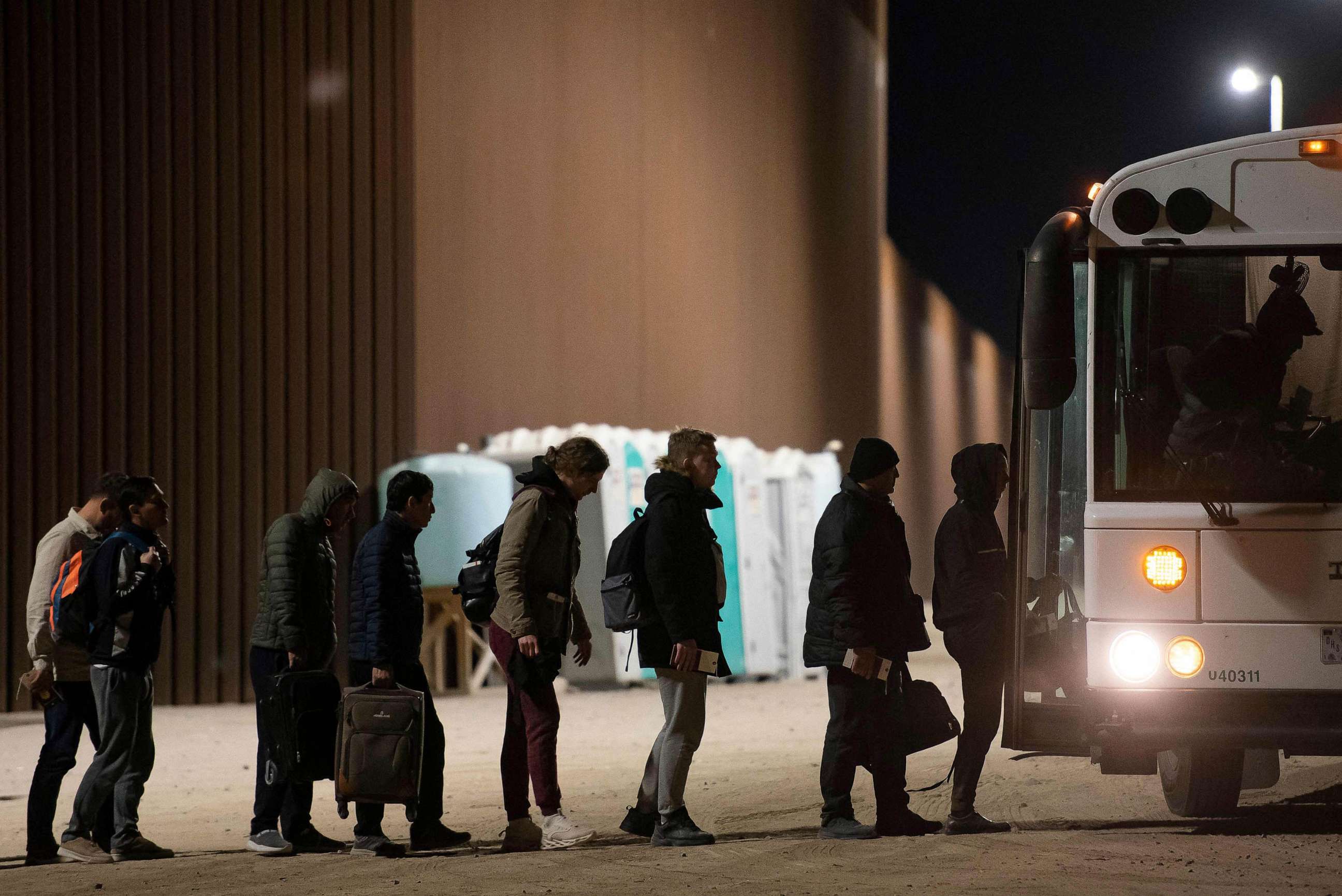 PHOTO: Asylum-seekers board a bus after being processed by US Customs and Border Patrol agents at a gap in the US-Mexico border fence near Somerton, Arizona, Dec. 26, 2022.