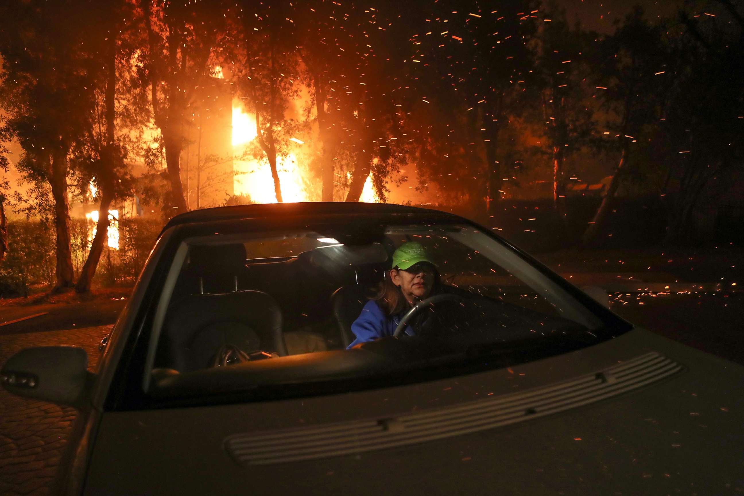 PHOTO: Tina Weeks jumps into her car to evacuate after her neighbors house became fully engulfed by the Woolsey Fire in Oak Park, Ca., in the early morning of Nov. 9, 2018.