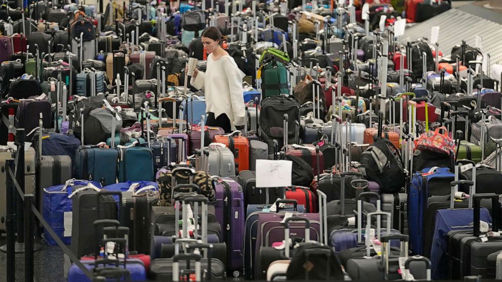 PHOTO: A woman walks through unclaimed bags at Southwest Airlines baggage claim at Salt Lake City International Airport, Dec. 29, 2022, in Salt Lake City.