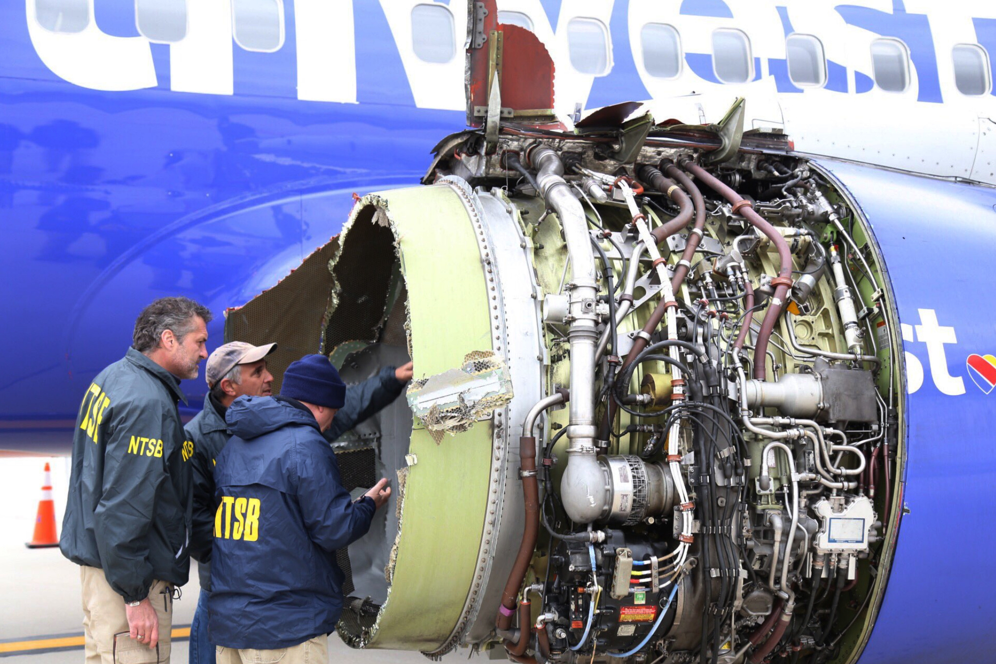 National Transportation Safety Board investigators examine damage to the engine of the Southwest Airlines plane that made an emergency landing at Philadelphia International Airport in Philadelphia on Tuesday.