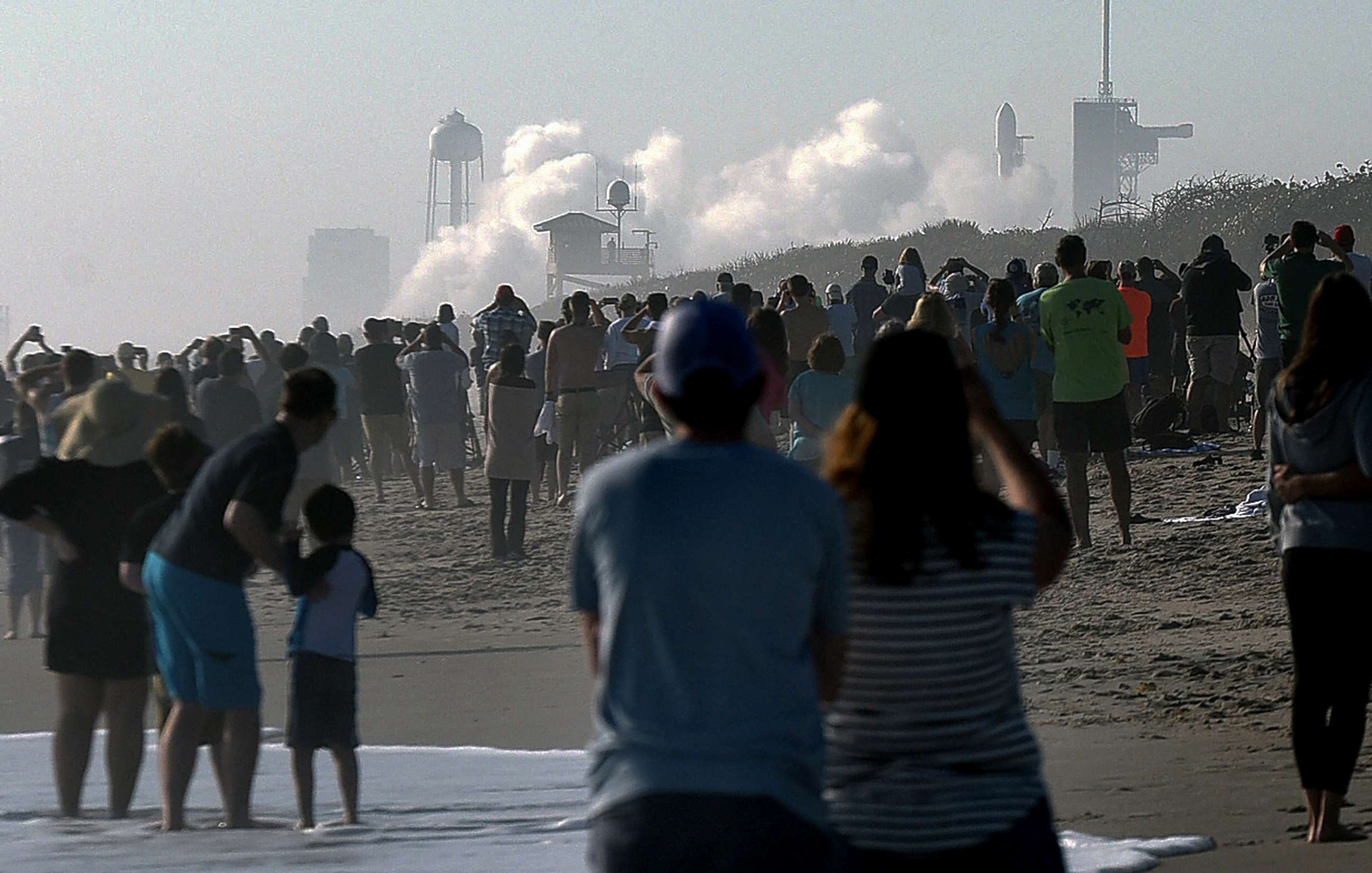 PHOTO: People watch from Playalinda Beach at Canaveral National Seashore as a cloud of smoke forms when a SpaceX Falcon 9 rocket carrying 60 Starlink satellites failed to launch, March 15, 2020.