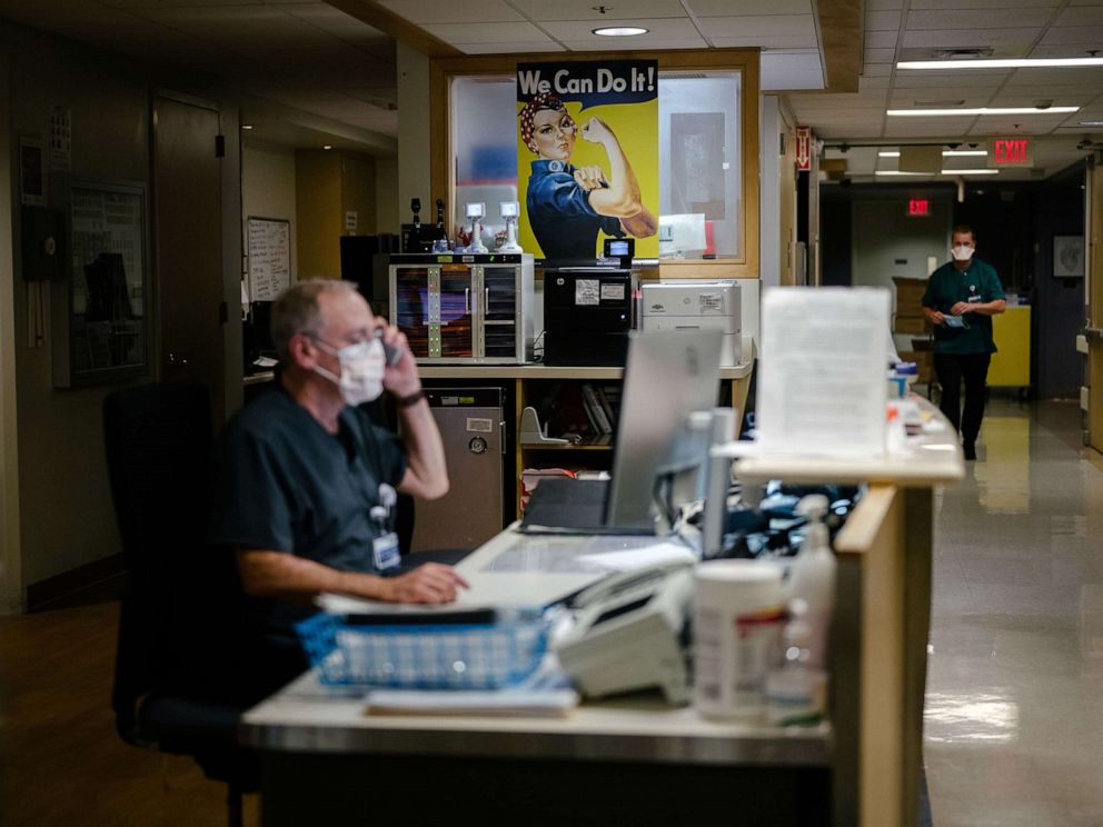 PHOTO: Rick Agrella, the assistant nurse manager at Providence Sacred Heart Medical Center, in Spokane, Wash., works on Sept. 10, 2021, in front of a Rosie the Riveter poster he put up in the intensive care unit in 2020 to help the staff stay motivated. 