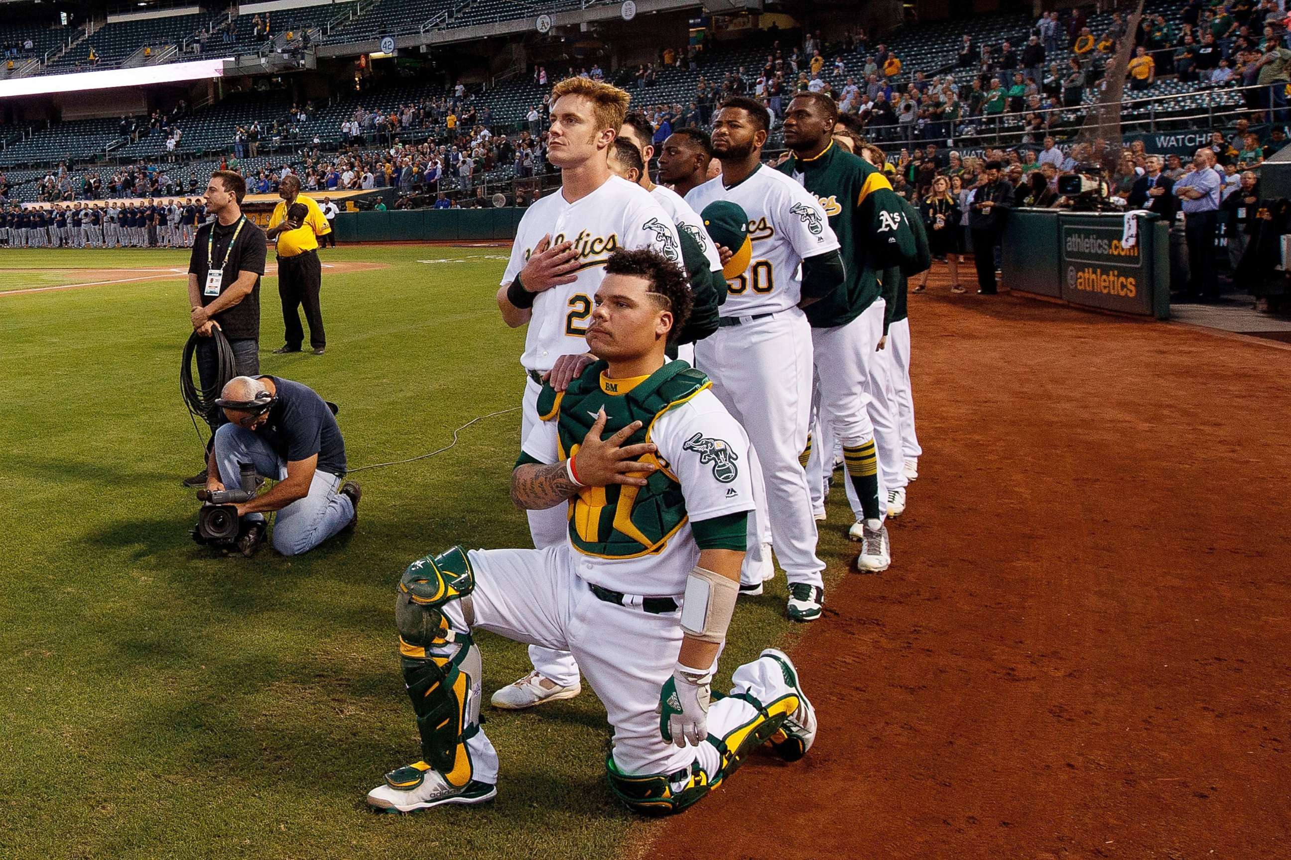PHOTO: Bruce Maxwell #13 of the Oakland Athletics kneels during the national anthem in front of teammate Mark Canha #20 before the game against the Seattle Mariners at the Oakland Coliseum, Sept. 25, 2017 in Oakland, California.