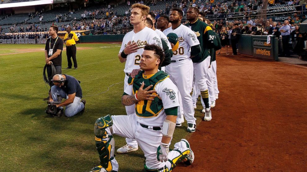 PHOTO: Bruce Maxwell #13 of the Oakland Athletics kneels during the national anthem in front of teammate Mark Canha #20 before the game against the Seattle Mariners at the Oakland Coliseum, Sept. 25, 2017 in Oakland, California.