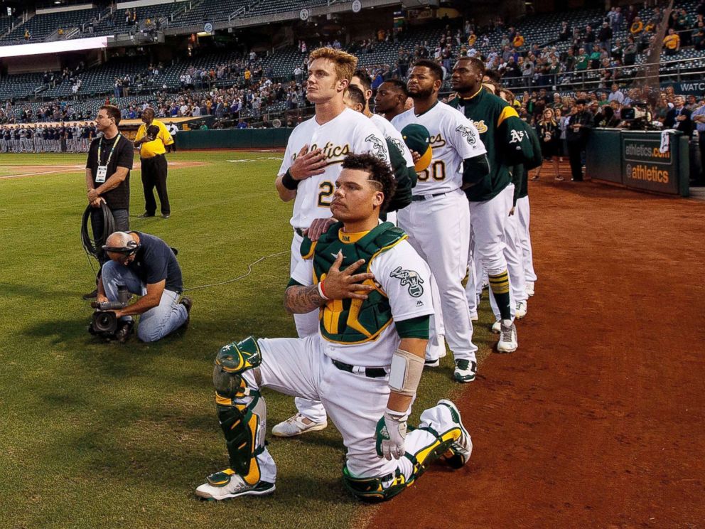 PHOTO: Bruce Maxwell #13 of the Oakland Athletics kneels during the national anthem in front of teammate Mark Canha #20 before the game against the Seattle Mariners at the Oakland Coliseum, Sept. 25, 2017 in Oakland, California.