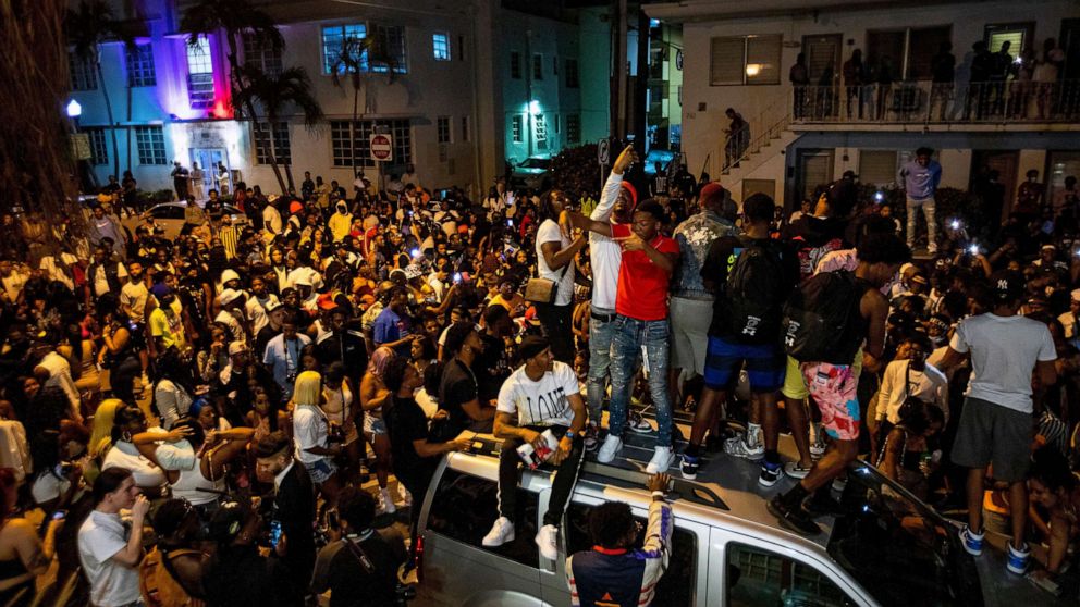 PHOTO: Crowds defiantly gather in the street while a speaker blasts music an hour past curfew in Miami Beach, Fla., March 21, 2021.