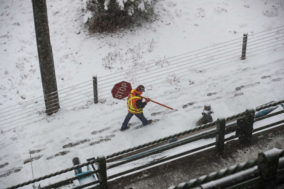 PHOTO: A construction worker carries a stop sign in the snow near the Brooklyn Bridge Park and I-278, April 2, 2018 in the Brooklyn borough of New York.