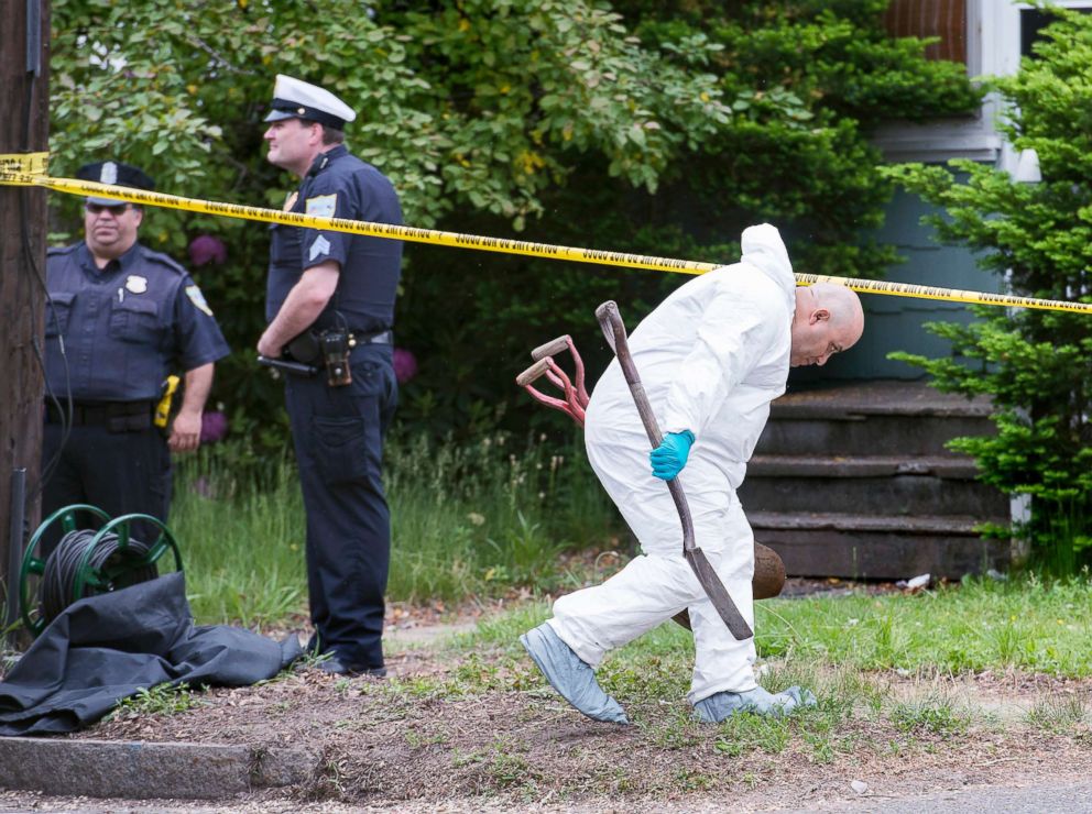 PHOTO: An investigator ducks under crime scene tape as he carries shovels after three bodies were found at a home in Springfield, Mass., June 1, 2018.