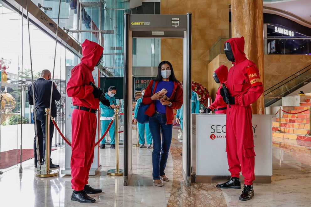PHOTO: A visitor walks through a checkpoint as mall security guards dressed in the Netflix series "Squid Game" costumes look on at Lotte Shopping Avenue in Jakarta, Indonesia, Oct. 20, 2021.