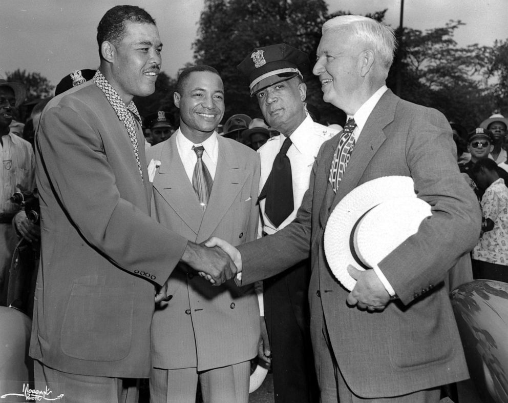 PHOTO: Former heavyweight boxer Joe Louis shakes hands with Chicago mayor Martin H. Kennelly at the Bud Billiken parade, sponsored by the Chicago Defender newspaper whose publisher, John H Sengstacke (second left) watches, in Chicago, in 1948. 