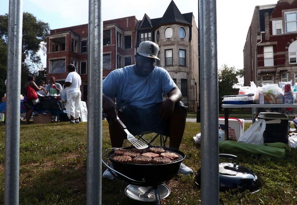 PHOTO: A man cooks hamburgers on a grill along the parade route during the 87th "Bud Billiken Parade" in Chicago, on Aug. 13, 2016.  