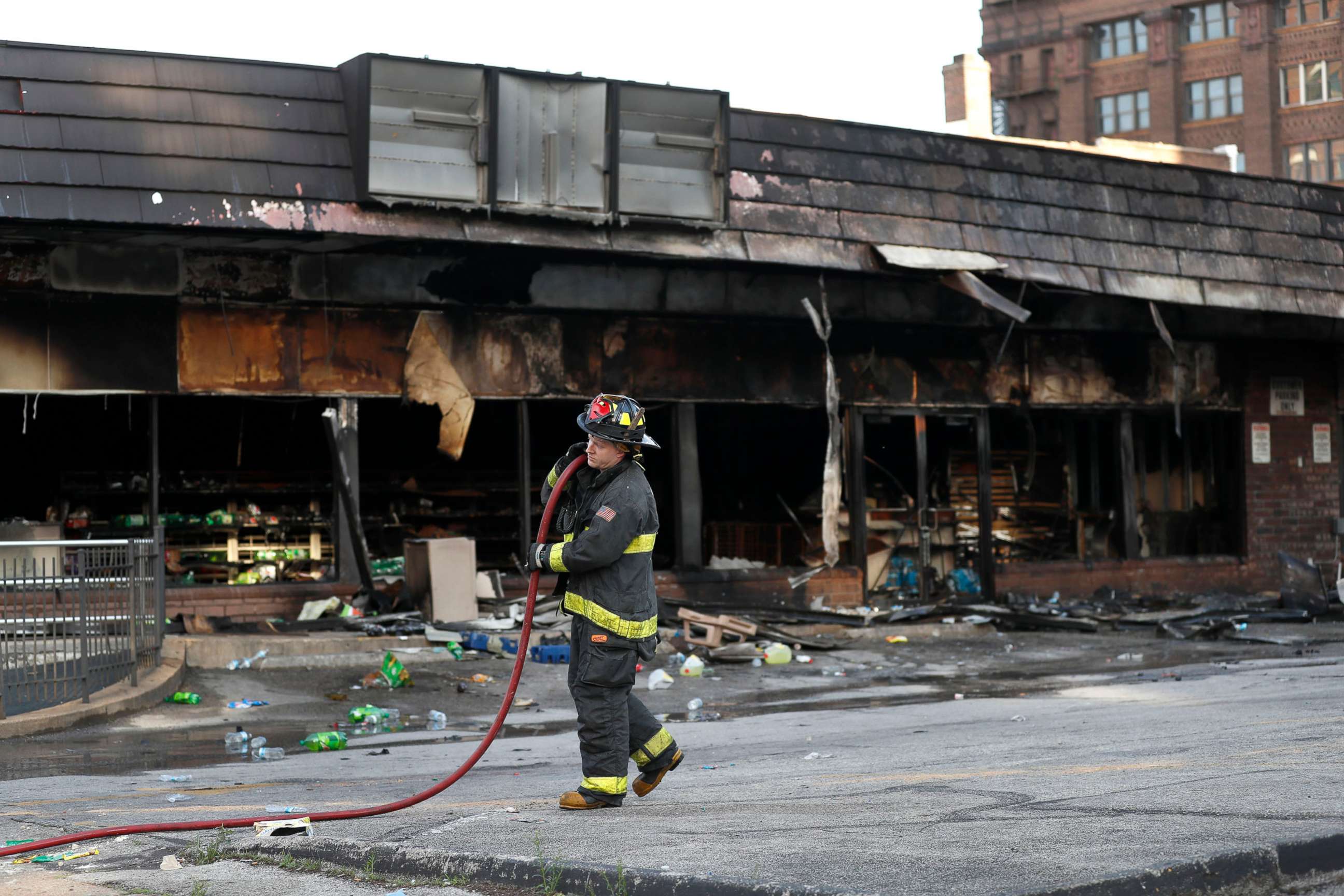 PHOTO: A member of the St. Louis Fire Department removes a hose outside a vandalized and burned convenience store, June 2, 2020, in St. Louis, the morning after protests against the death of George Floyd.