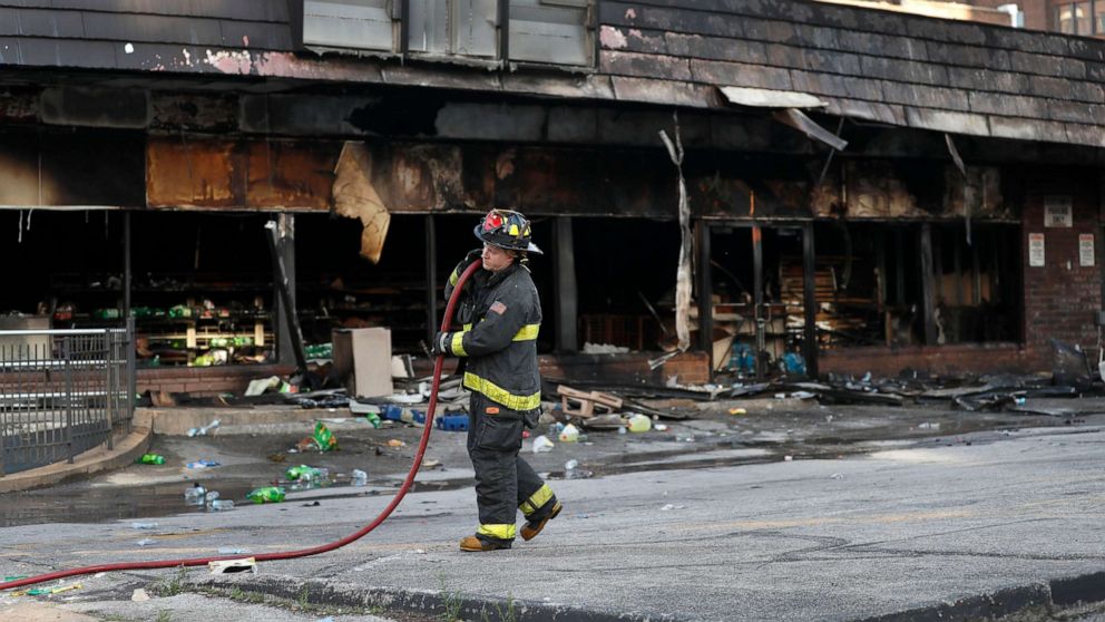 PHOTO: A member of the St. Louis Fire Department removes a hose outside a vandalized and burned convenience store, June 2, 2020, in St. Louis, the morning after protests against the death of George Floyd.