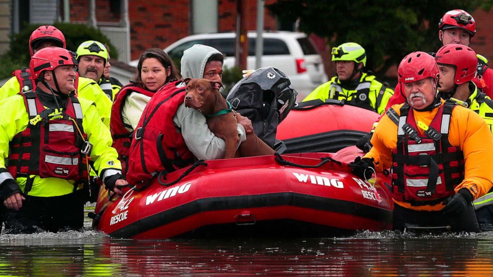 PHOTO: Matthew Robinson holds onto his dog Bebe as and Kimberly Tat are rescued from their home by first responders from Central County Fire and Rescue along Main Street in Old Towne St. Peters, Mo., on Tuesday, July 26, 2022.