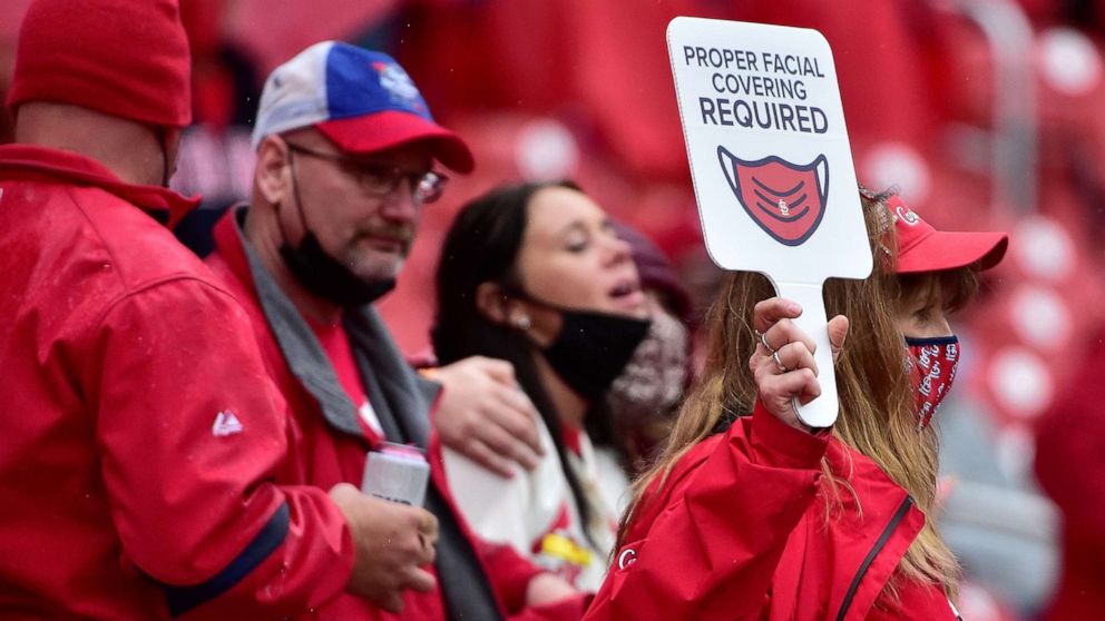PHOTO:  An usher walks through the aisles and carries a sign reminding fans to wear their mask during the seventh inning of the home opener against the Milwaukee Brewers at Busch Stadium in St Louis, Mo., April 8, 2021.