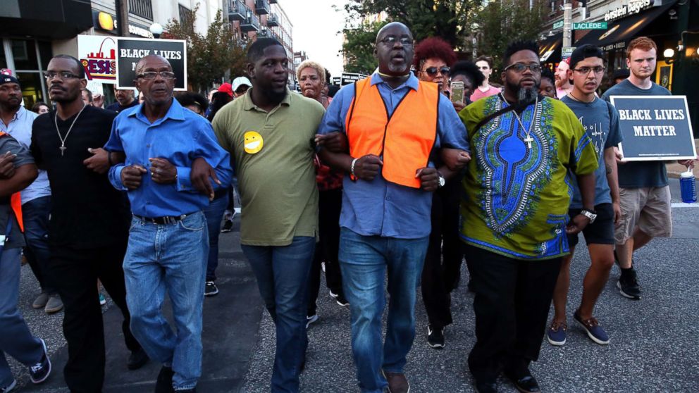 PHOTO: Pastor Clinton Stancil, center right, of Wayman AME Church locks arms with fellow clergy members as they lead hundreds of people protesting down Euclid Avenue, Sept. 15, 2017, in the Central West End.