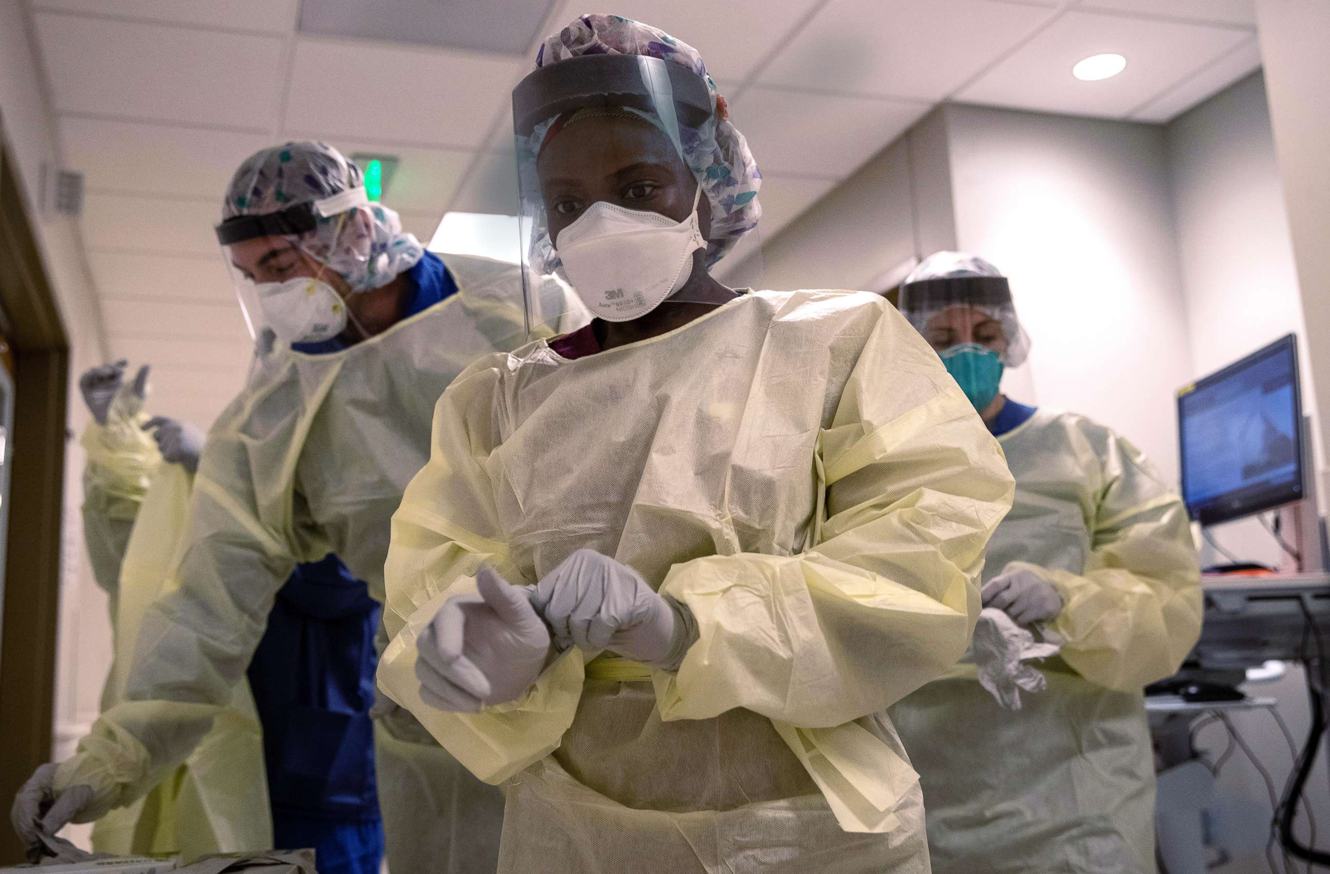 PHOTO: Medical workers dons personal protective equipment before entering the room of a patient with COVID-19 in a Stamford Hospital intensive care unit, on April 24, 2020, in Stamford, Conn.