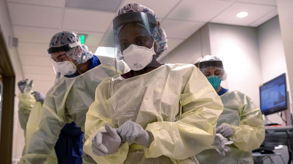 PHOTO: Medical workers dons personal protective equipment before entering the room of a patient with COVID-19 in a Stamford Hospital intensive care unit, on April 24, 2020, in Stamford, Conn.