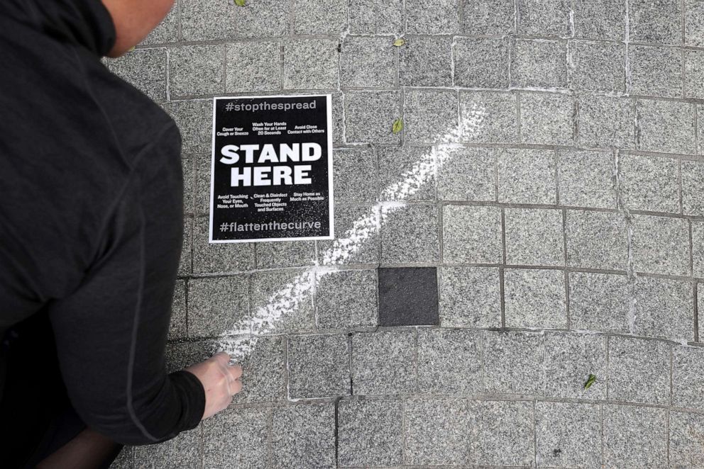 PHOTO: Workers use a tape measure mark spaces six feet apart for people to wait in line safely as they convert the outdoor plaza into a grab-and-go meal restaurant in response to the novel coronavirus March 17, 2020, in Washington, D.C. 