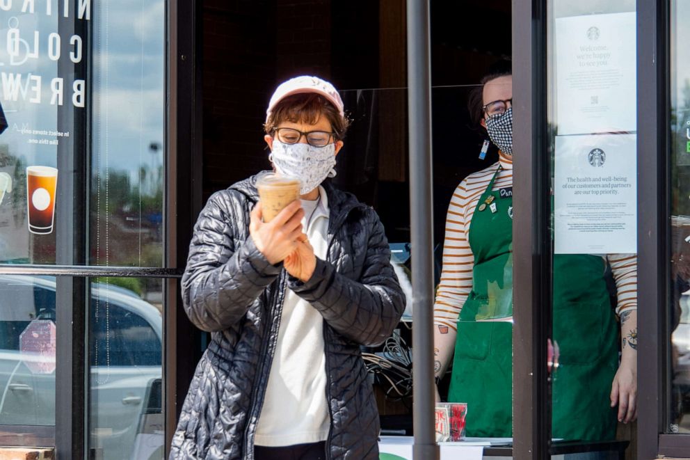 PHOTO: A Starbucks customer checks her order as Ohio businesses reopen in the wake of the Coronavirus COVID-19 pandemic, Tuesday, May 12, 2020, in Cincinnati, Ohio, United States.