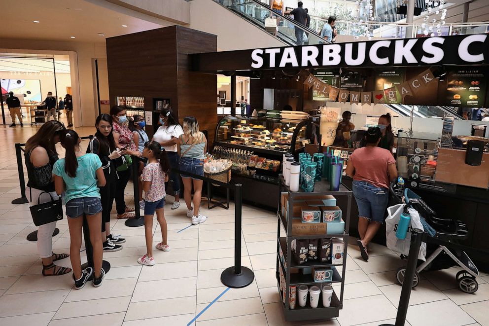 PHOTO: Consumers wait in line at a  Starbucks location as they return to retail shopping at the Arrowhead Towne Center, June 20, 2020, in Glendale, Arizona.