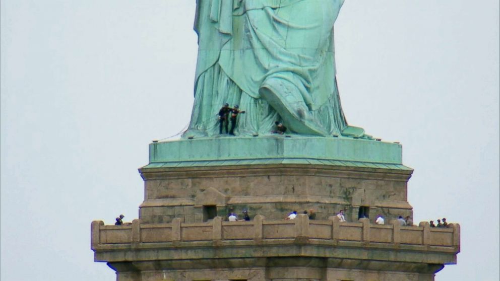 PHOTO: Police approach a woman who climbed the base of the Statue of Liberty in New  York City on July 05, 2018.