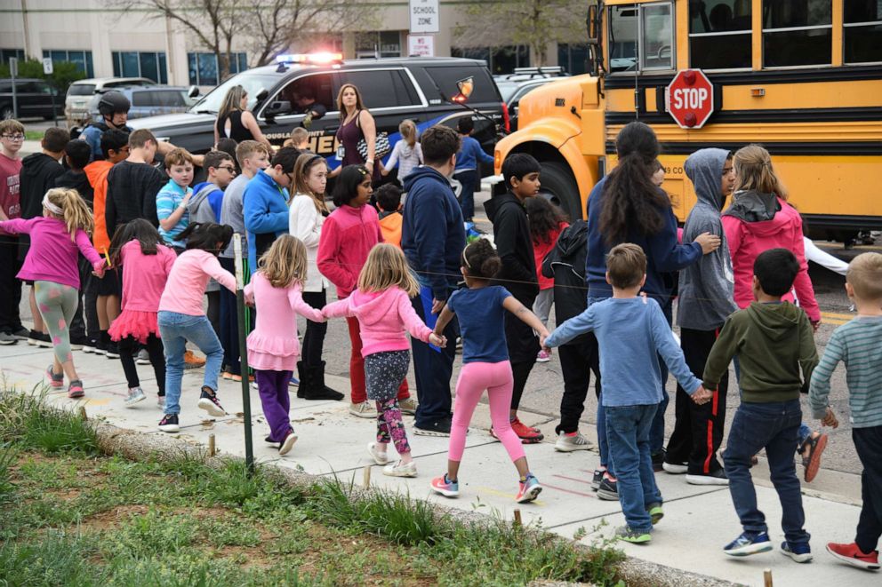 PHOTO: Students are escorted to a school bus in front of STEM School Highlands Ranch after a shooting, May 7, 2019, in  Highlands Ranch, Colo. 