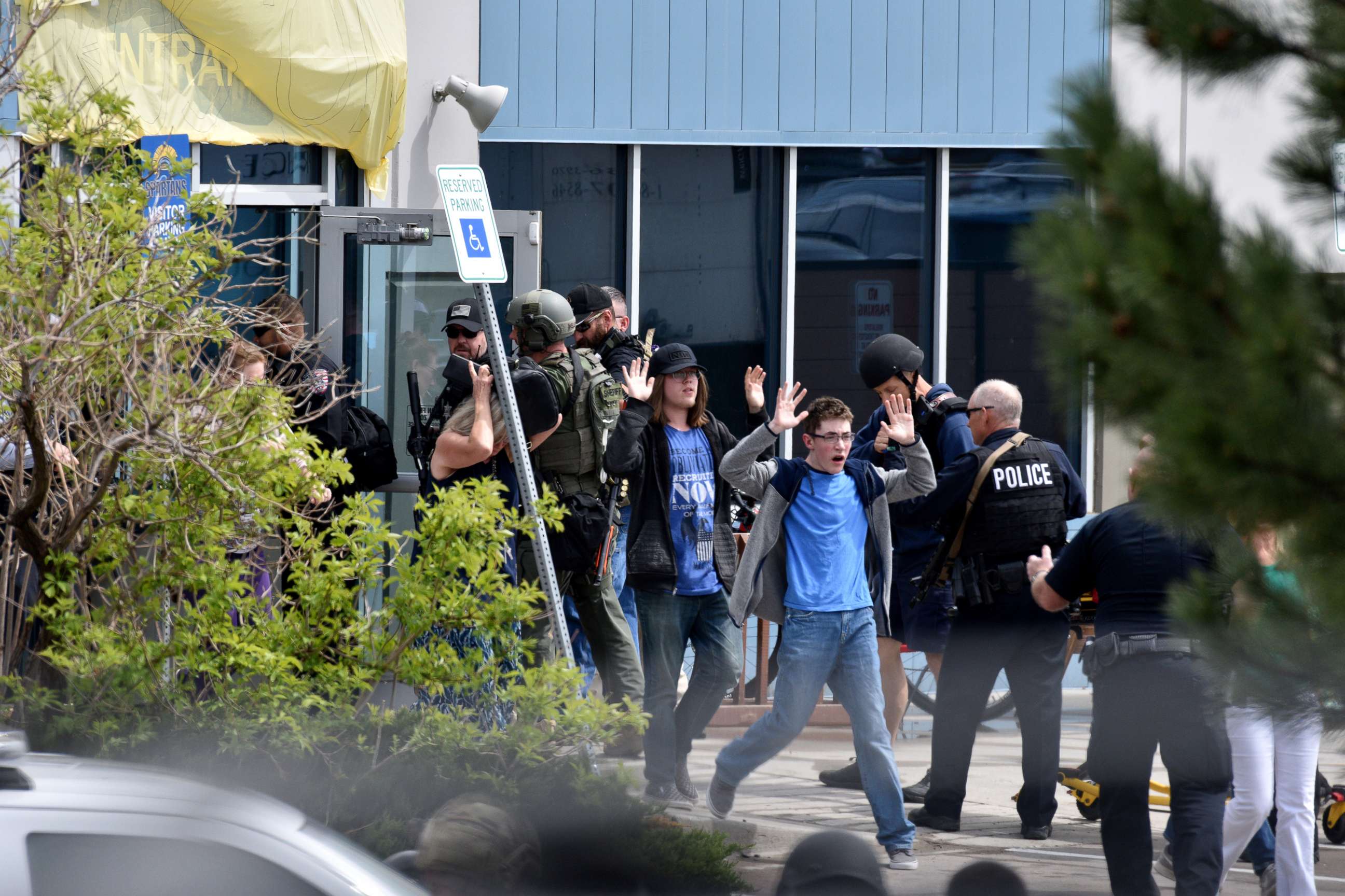 PHOTO: Students and teachers raise their arms as the exit the scene of a shooting in which at least seven students were injured at the STEM School Highlands Ranch, May 7, 2019, in Highlands Ranch, Colo.