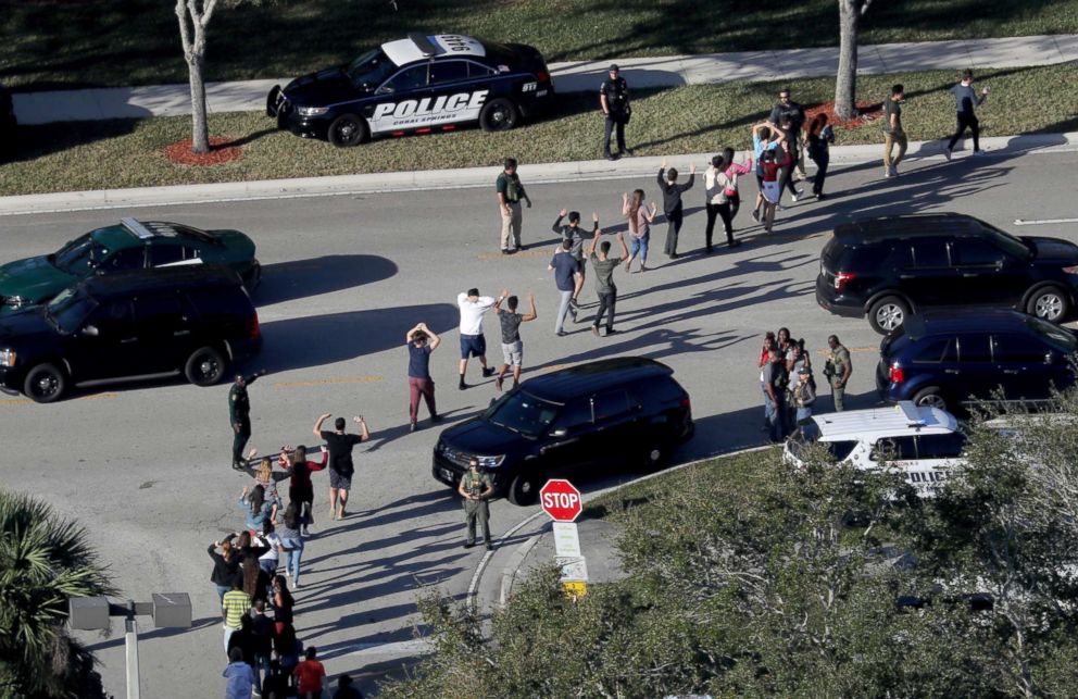 PHOTO: Students hold their hands up as they are evacuated by police from Marjory Stoneman Douglas High School in Parkland, Fla., after a shooter opened fire on the campus on Feb. 14, 2018.