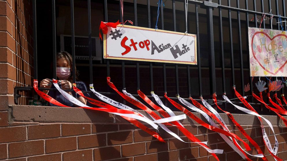PHOTO: Parent Coordinator Christina Pun puts up ribbons with messages of peace, love and hope in front of Yung Wing School P.S. 124 on May 21, 2021, in New York.