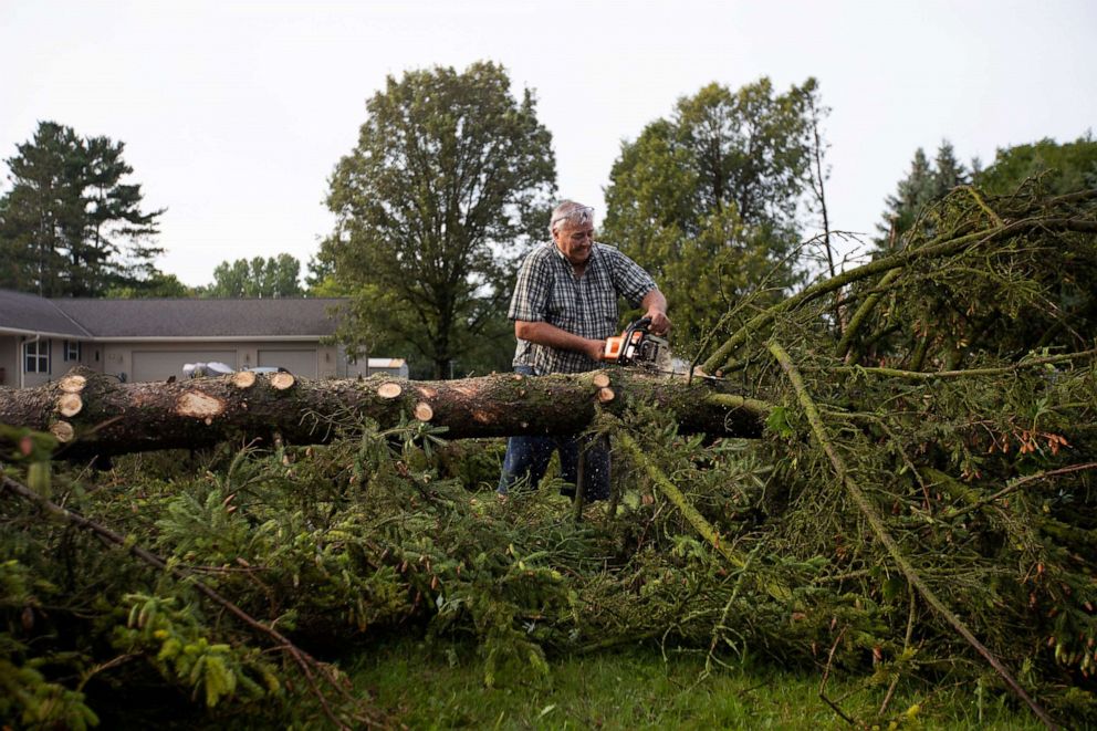 PHOTO: Robert Rudnick chainsaws a fallen tree on his property on Chicago Street, on Aug. 11, 2021, in Pulaski, Wis.