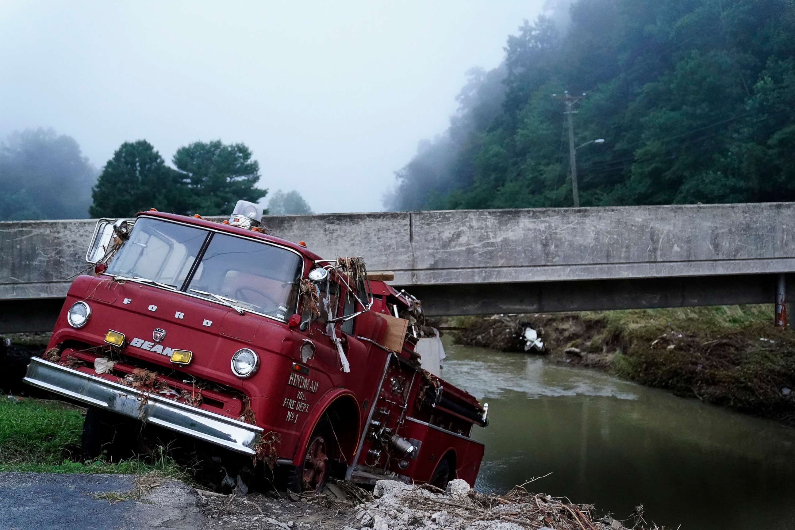 PHOTO: A fire truck is seen hangin over the edge of the water propped against a bridge, Aug. 3, 2022, in Hindman, Ky., after massive flooding carried the fire truck towards the water.  