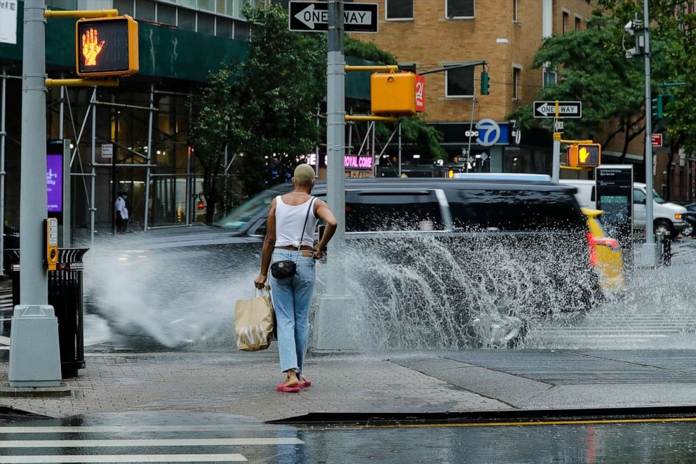 PHOTO: A pedestrian avoids being splashed by passing automobiles during heavy rain brought by Tropical Storm Fay, July 10, 2020, in New York.