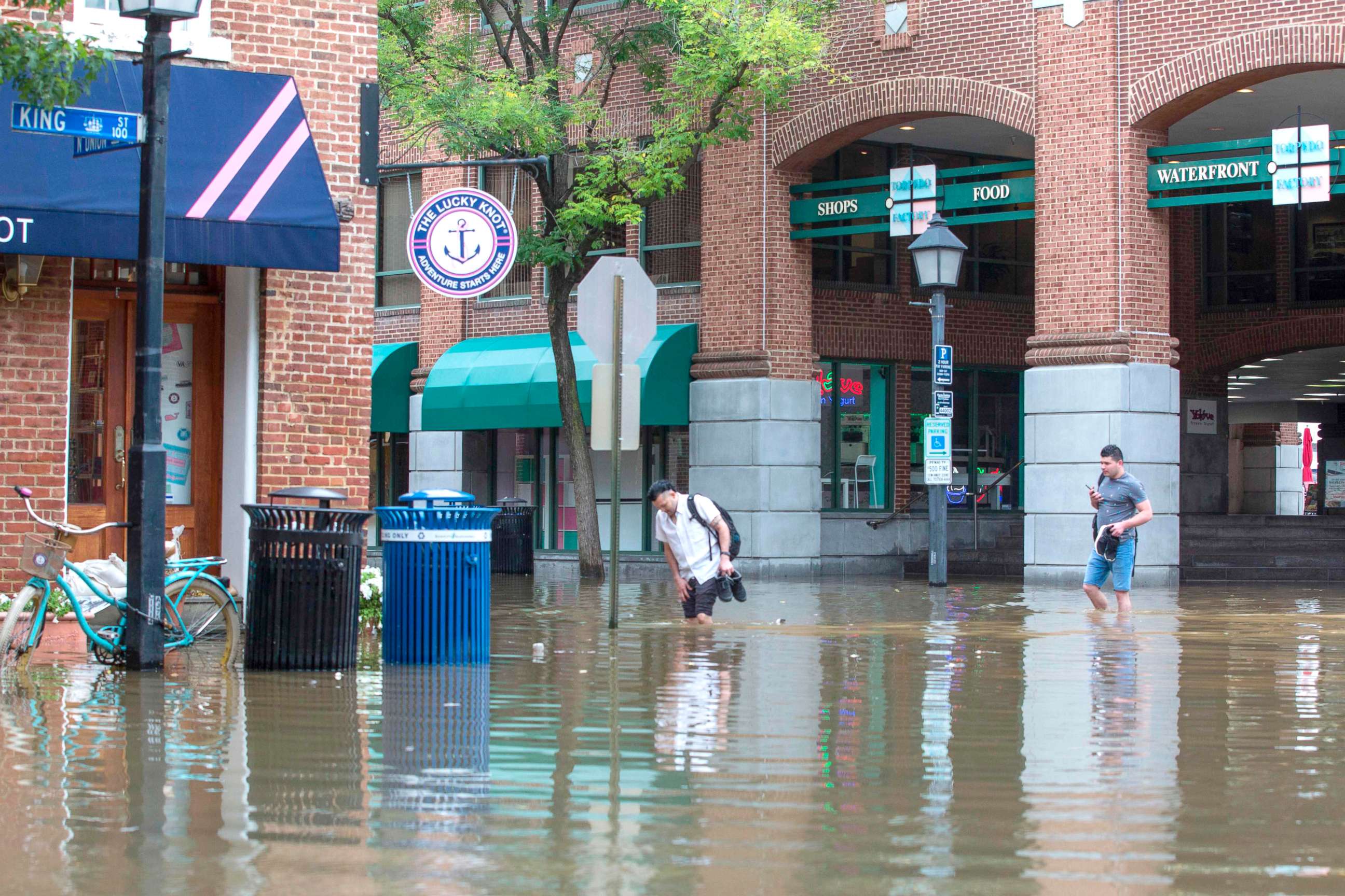 PHOTO: People cross the street as water floods outside buildings in Old Town Alexandria, Va., Sept. 11, 2018.