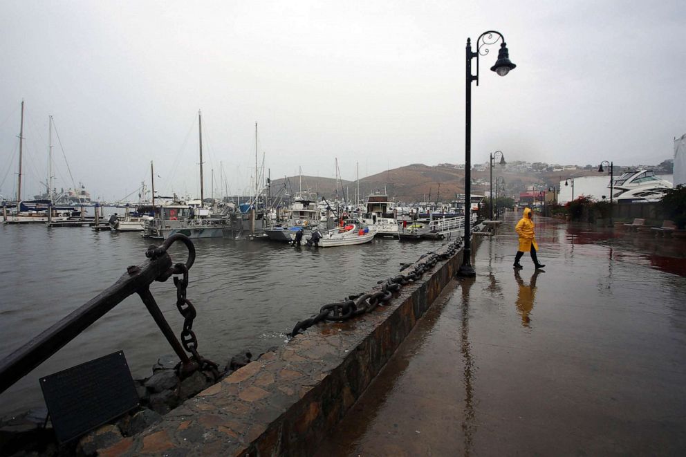 PHOTO: A person wearing a yellow rain coat walks at the port in Ensenada as Tropical Storm Hilary hits Baja California state, Mexico, Aug. 20, 2023.