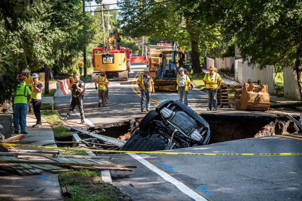 PHOTO: Workers gather around a portion of county road in Demarest, N.J., that collapsed during Tropical Storm Ida trapping at least one car, Sept. 02, 2021.