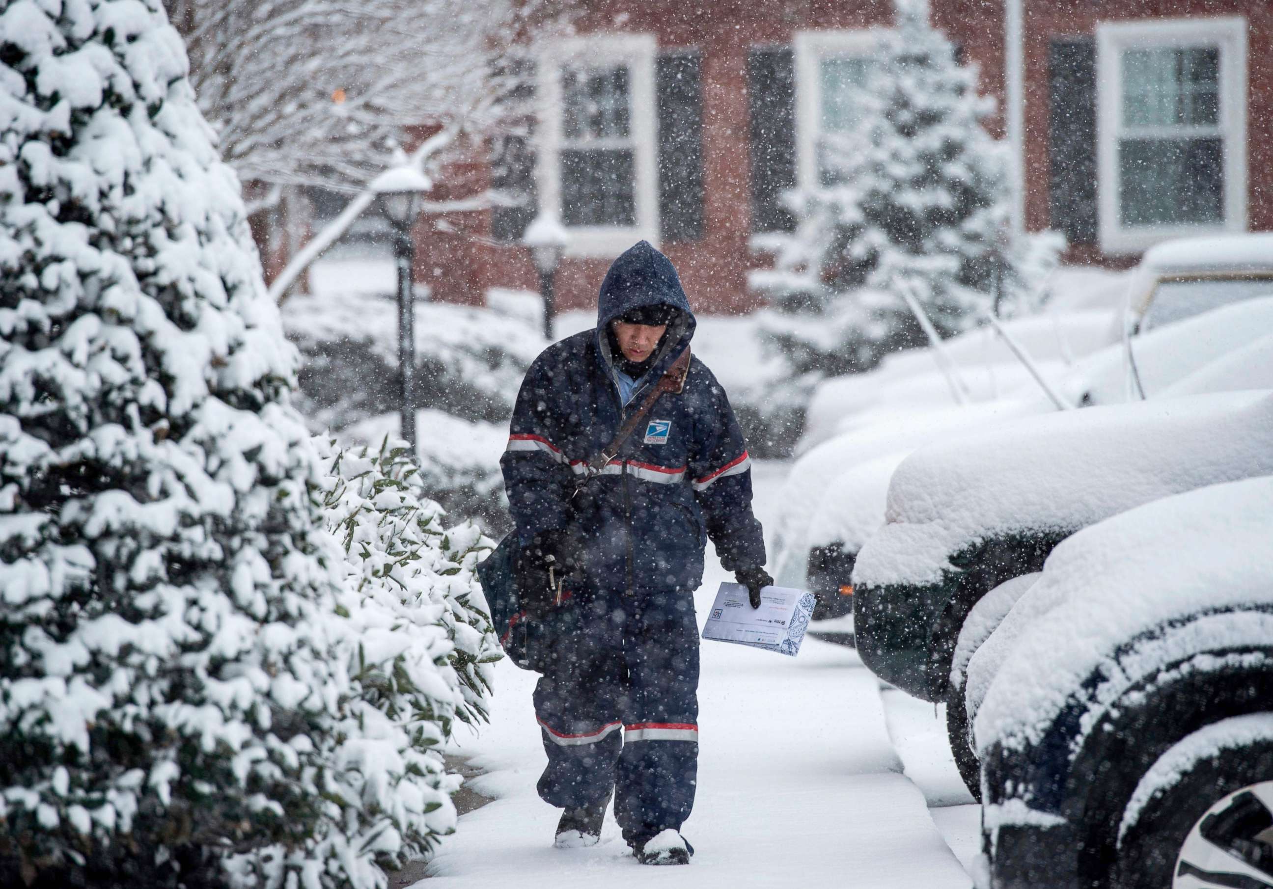 PHOTO: A postman walks through snow to deliver mail during the latest storm to hit the U.S. east coast, March 21, 2018, in Arlington, Va.