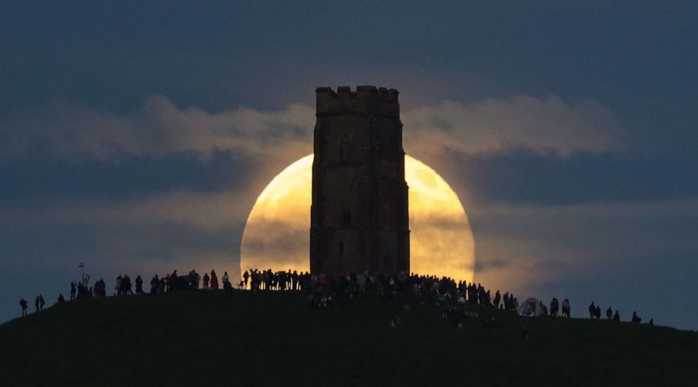 PHOTO: In this June 20, 2016, file photo, a strawberry moon rises behind Glastonbury Tor as people gather to celebrate the summer solstice in Somerset, England.