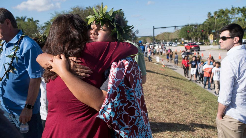 PHOTO: People embrace as students and parents arrive for voluntary campus orientation at the Marjory Stoneman Douglas High School, for the coming Wednesday's reopening, following last week's mass shooting in Parkland, Fla., Feb. 25, 2018.