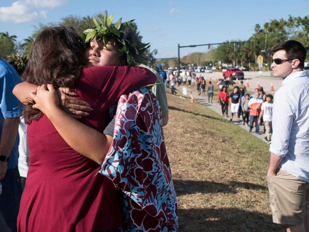 PHOTO: People embrace as students and parents arrive for voluntary campus orientation at the Marjory Stoneman Douglas High School, for the coming Wednesdays reopening, following last weeks mass shooting in Parkland, Fla., Feb. 25, 2018.