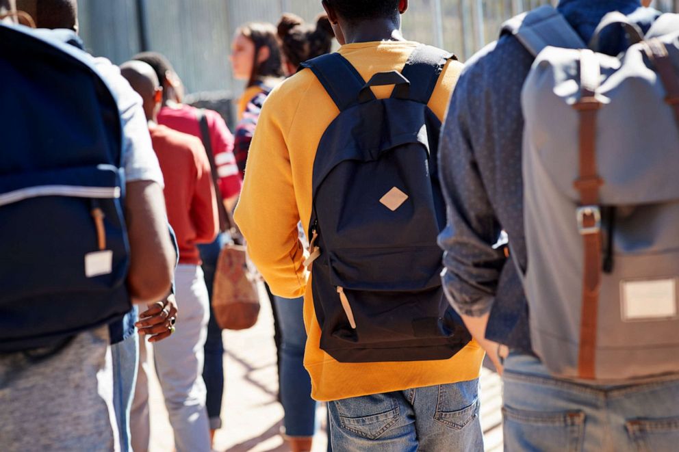 PHOTO: Rear view of students walking at a school campus.