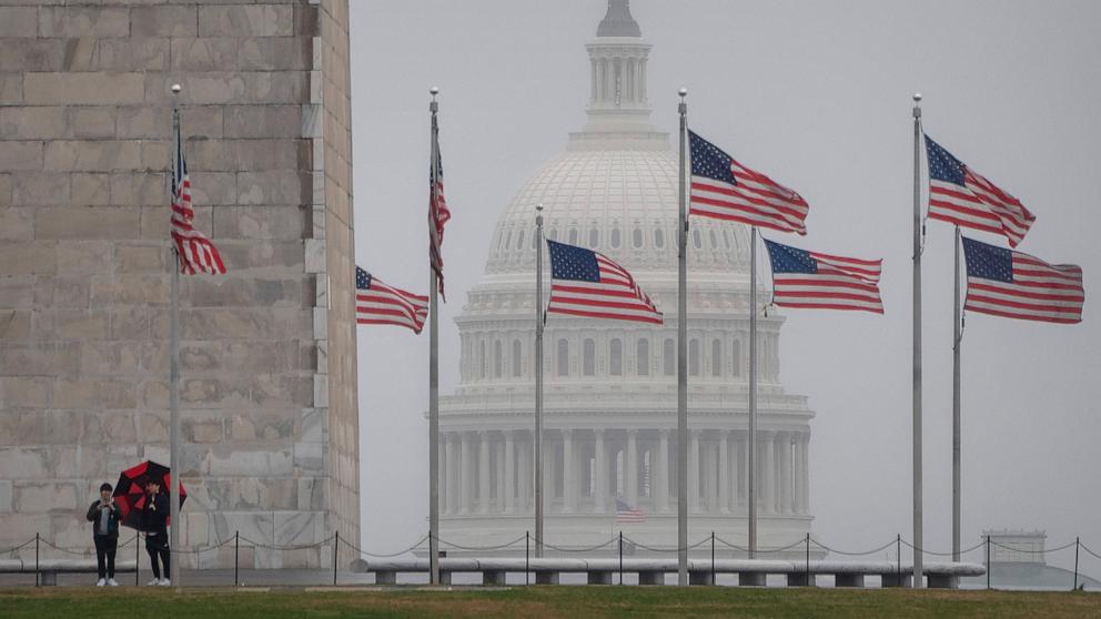 PHOTO: Visitors stand at the base of the Washington Monument as the dome of the Capitol is seen in the distance on a rainy morning, Mar. 5, 2024, in Washington. 
