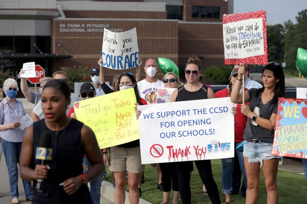 PHOTO: A TV news reporter films a hit in front of supporters of the Cherokee County School District's decision to reopen schools to students during the coronavirus pandemic as they rally outside the headquarters in Canton, Georgia, on Aug. 11, 2020.