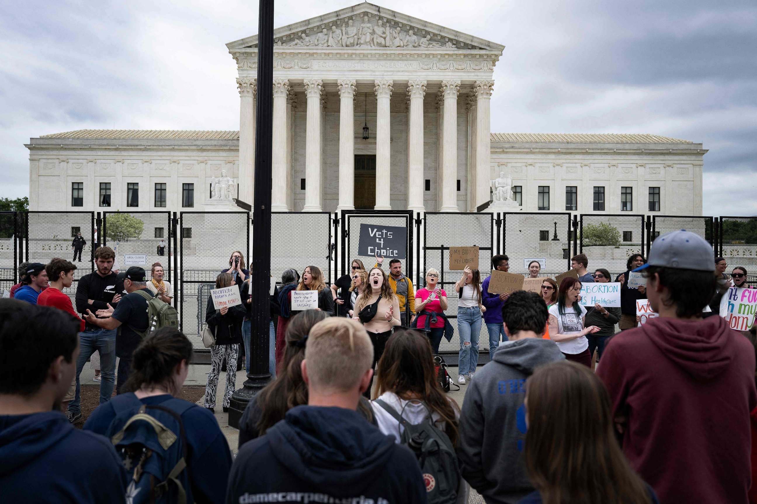 PHOTO: A line of pro-life demonstrators watch as Pro-choice demonstrators chant in front of an un-scalable fence that stands around the US Supreme Court in Washington, D.C., on May 5, 2022.