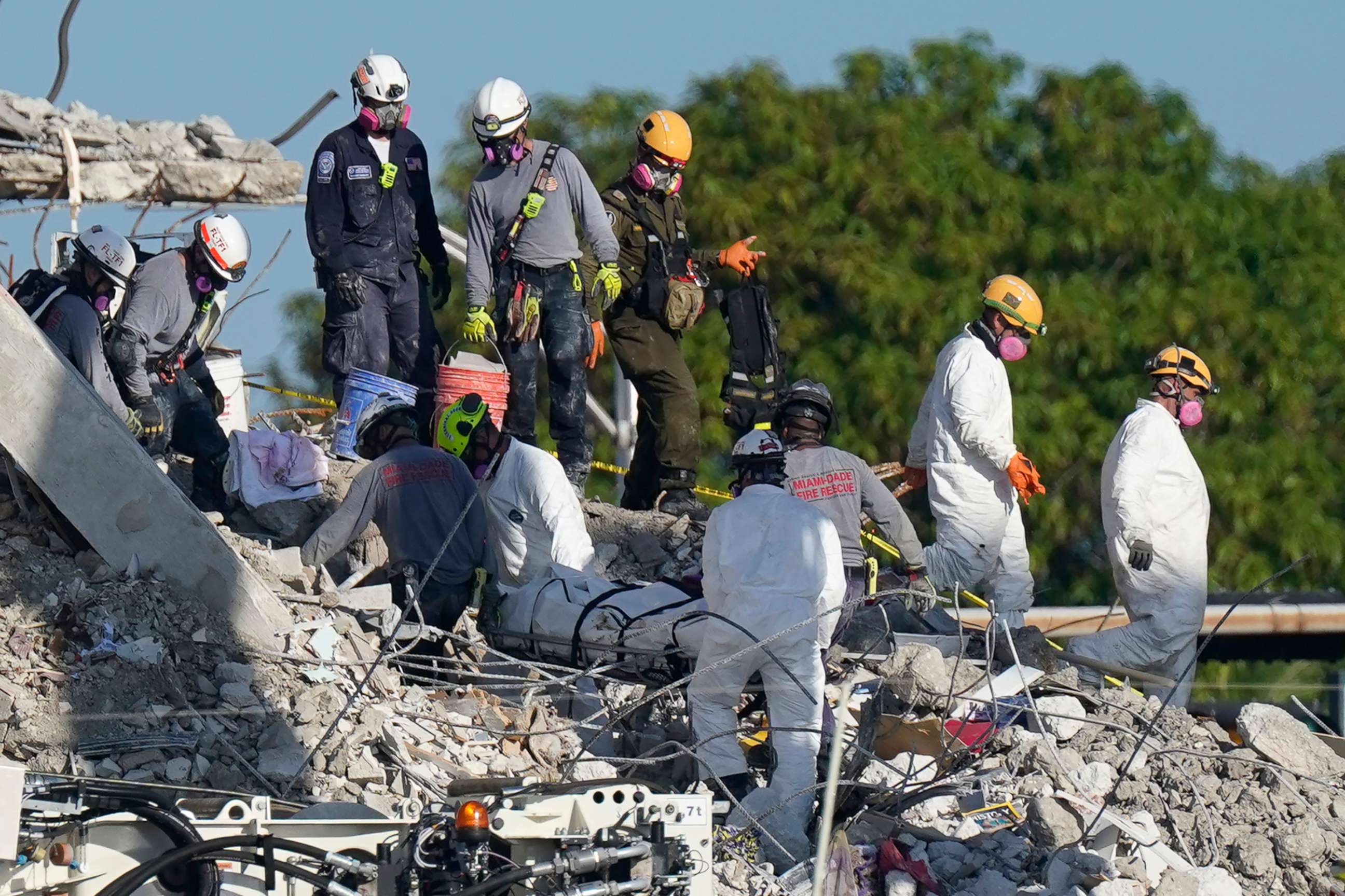 PHOTO: Search and rescue personnel remove remains on a stretcher as they work atop the rubble at the Champlain Towers South condo building where scores of people remain missing more than a week after it partially collapsed, July 2, 2021, in Surfside, Fla.
