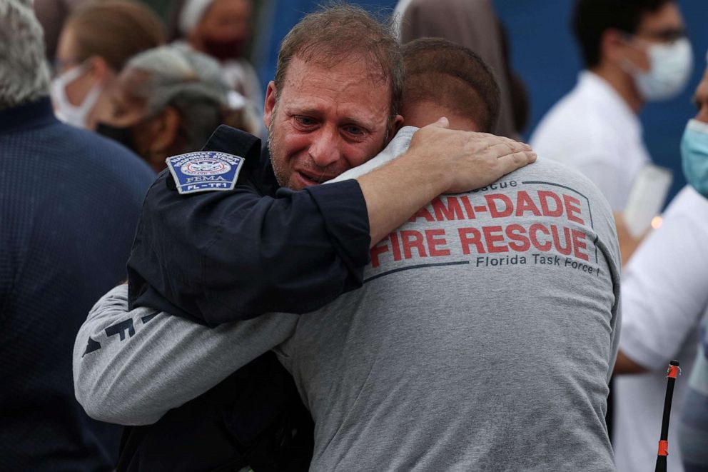 PHOTO: Rescue workers with the Miami Dade Fire Rescue embrace after a moment of silence near the memorial site for victims of the collapsed 12-story Champlain Towers South condo building in Surfside, Fla., July 07, 2021. 